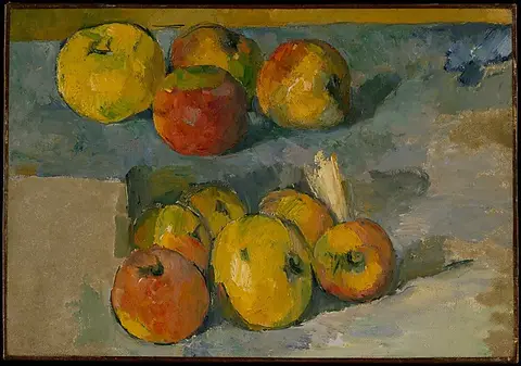 Red and yellow apples on a table against a grey-blue wall