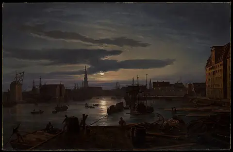 A night harbor with ships and buildings under a cloudy sky lit by the moon