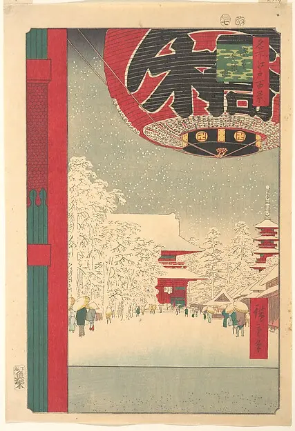 A huge red paper lantern in the foreground with a snowy temple street behind it