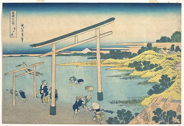 A torii gate standing in shallow blue bay water with small figures wading