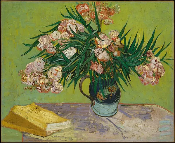Pink oleander flowers in a pitcher against a bright yellow-green wall
