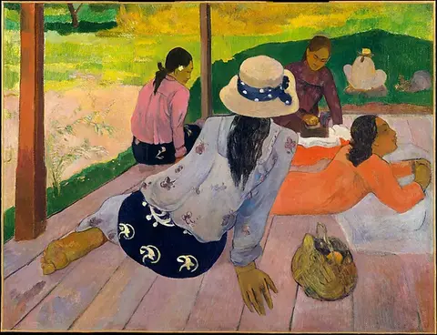 Tahitian women sitting on a porch in pink, orange and blue clothing above green grass
