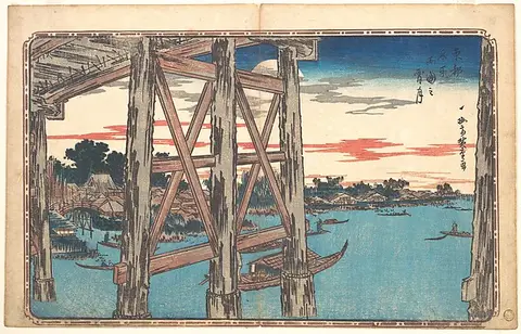 Wooden bridge supports in the foreground with a pink sunset over a blue river