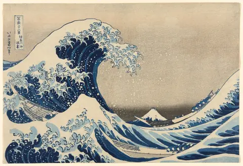 A huge cresting wave over two boats with Mount Fuji in the background